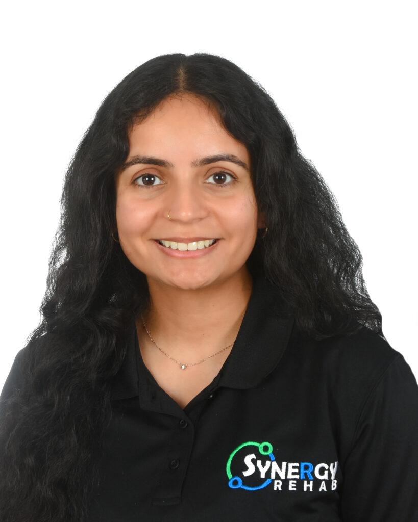 Professional headshot of Anup Dhaliwal, a physiotherapist, wearing a black polo shirt.